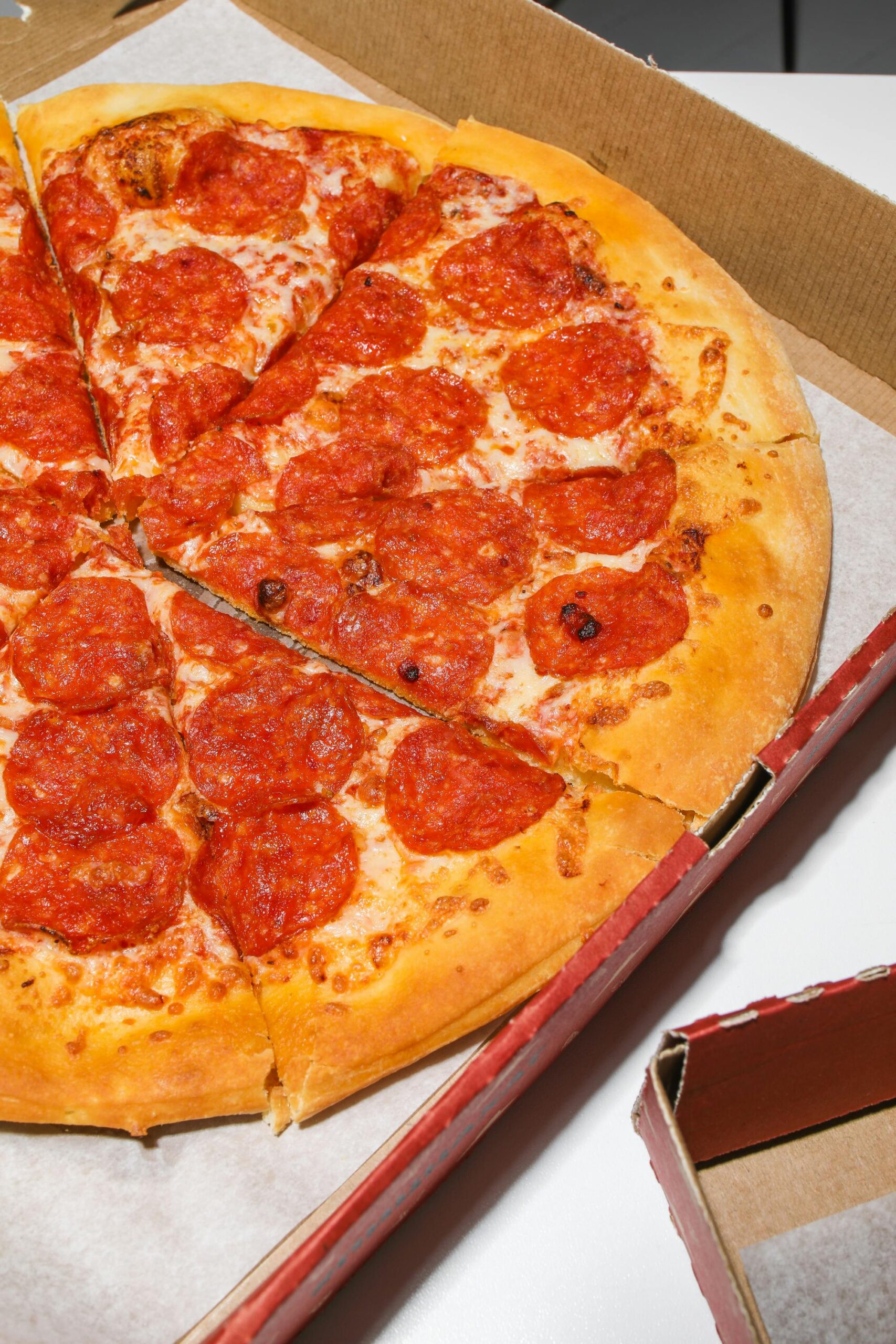 Freshly baked pepperoni pizza in an open cardboard box, cheese melted perfectly.